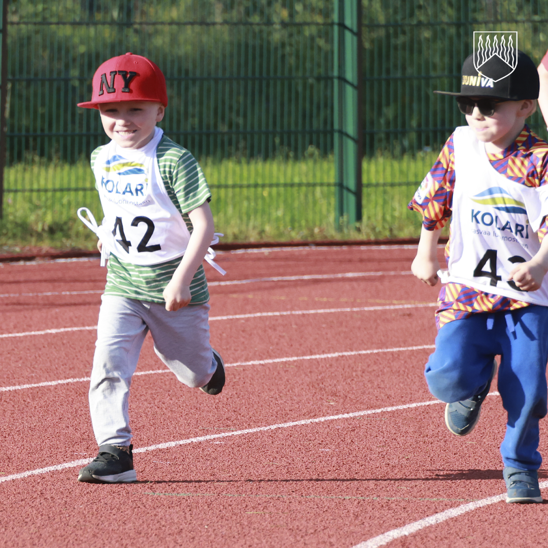 Kaksi lasta juoksemassa urheilukentällä sarjajuoksuissa.